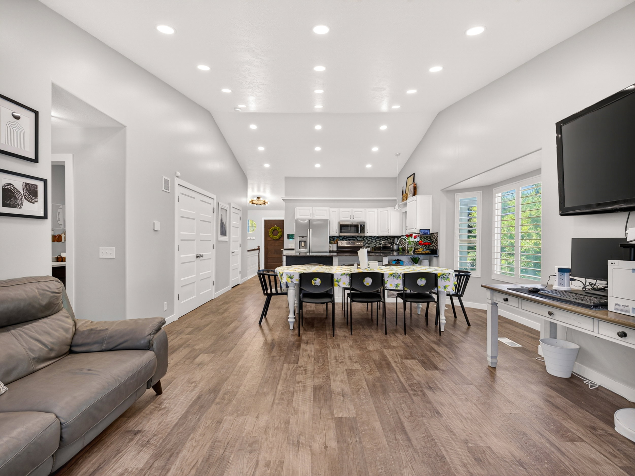 Open-concept living area featuring vaulted ceilings with recessed lighting, wood-finish flooring, and white interior doors
