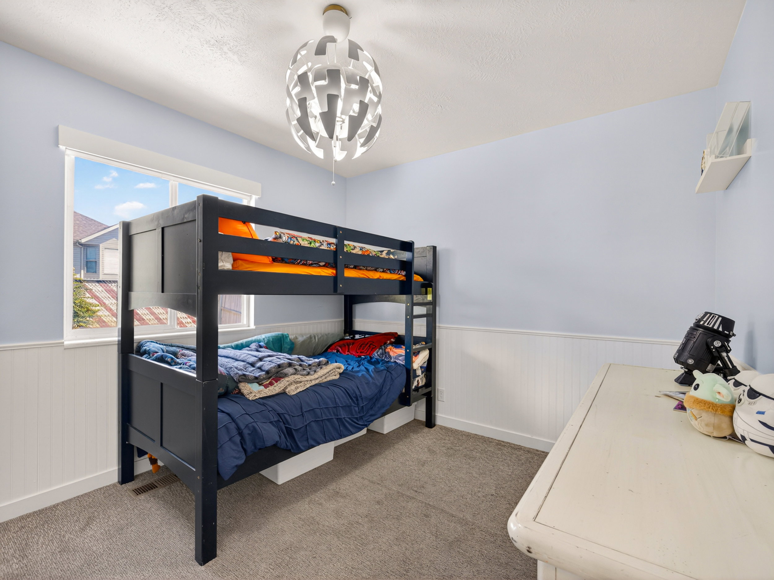 Bedroom featuring light blue walls with wainscoting, a double-pane window, and a contemporary ceiling fixture