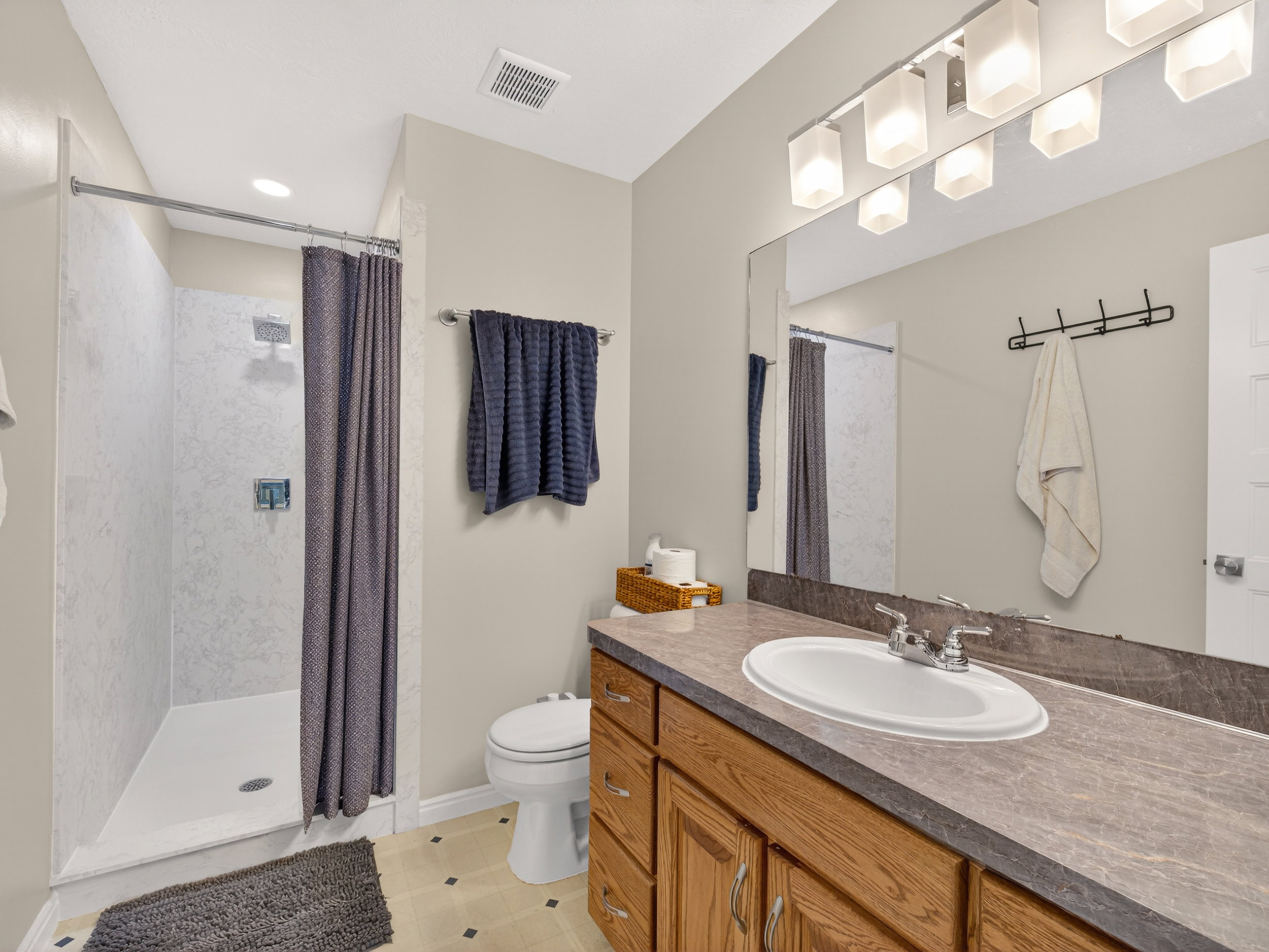 Primary Bathroom featuring a single vanity with wood cabinetry, a large mirror, and an oval sink