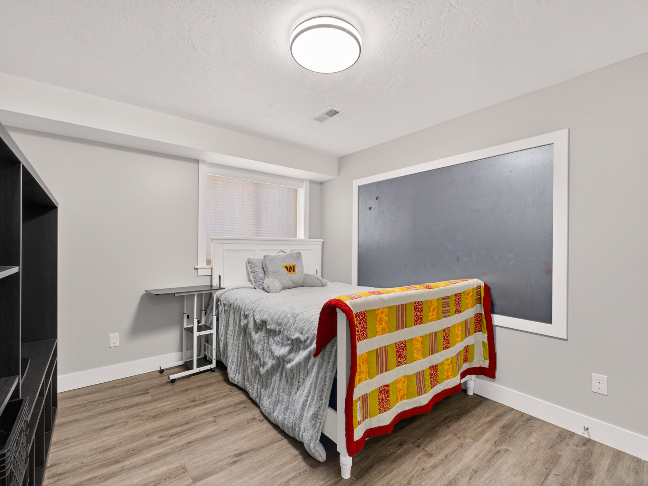 Room featuring wood-finish flooring, a contemporary flush-mount ceiling light, white baseboards, and a window with blinds