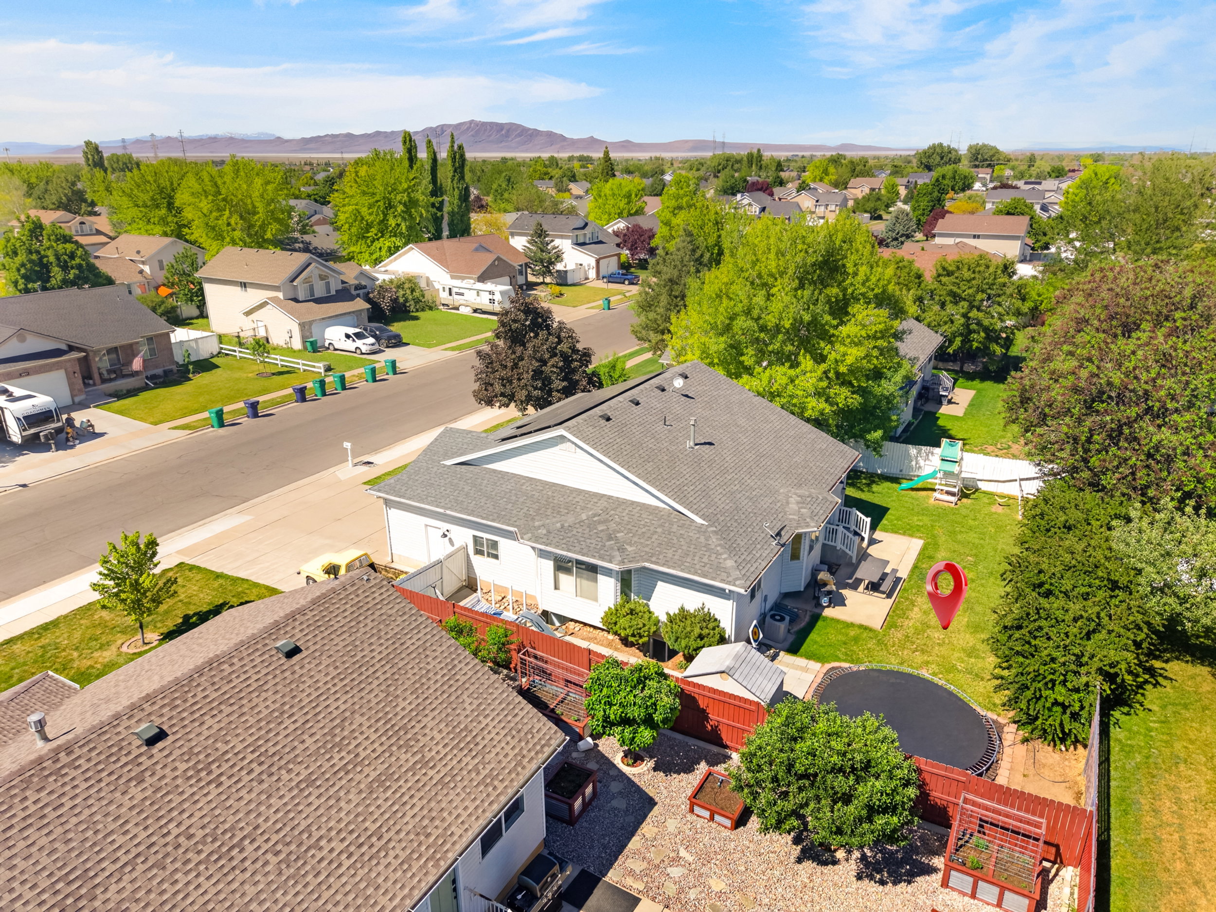 Expansive backyard with a manicured lawn, concrete patio, and established trees