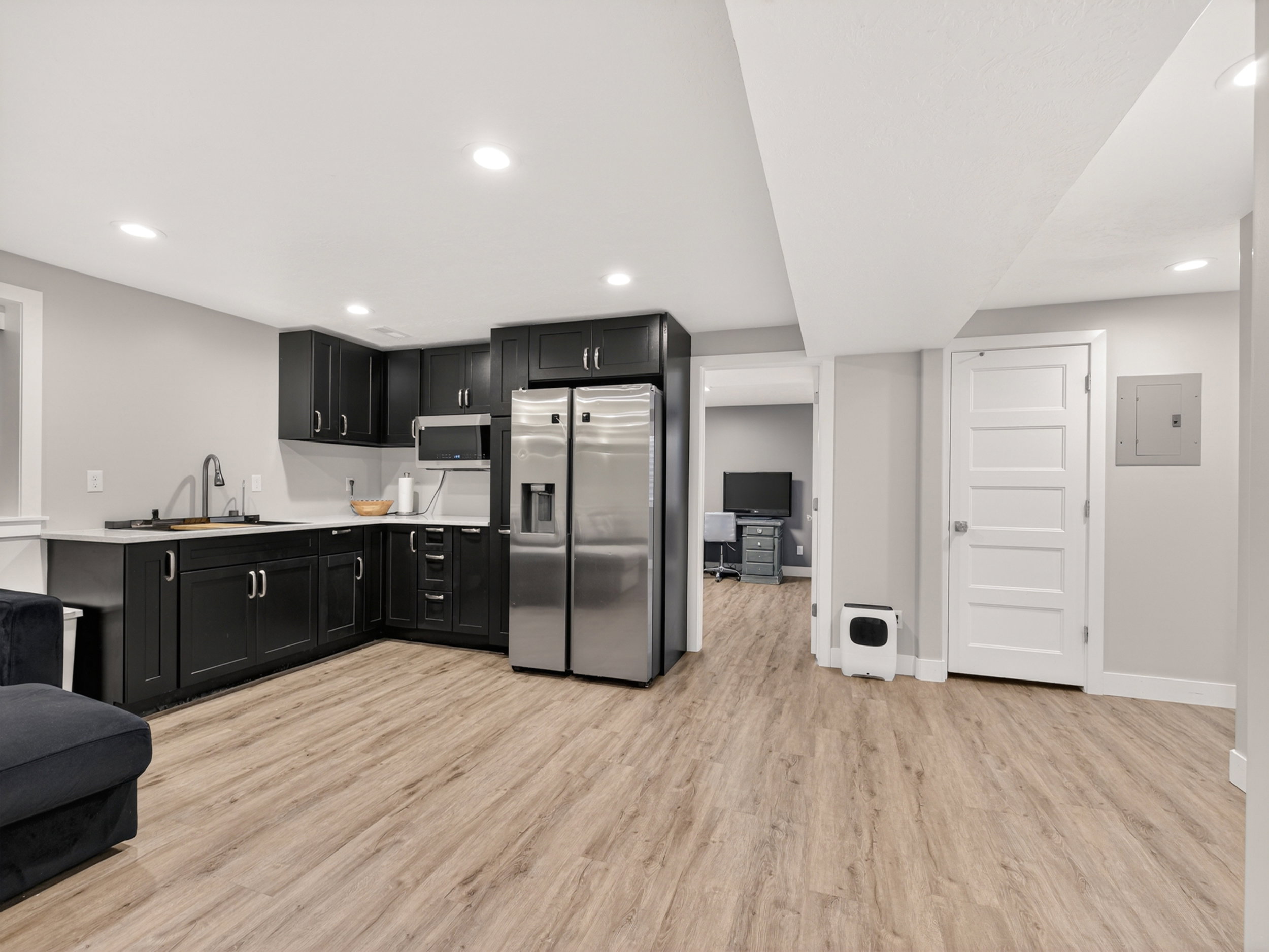 Corner kitchenette featuring dark cabinetry, stainless steel appliances, and a light-toned countertop