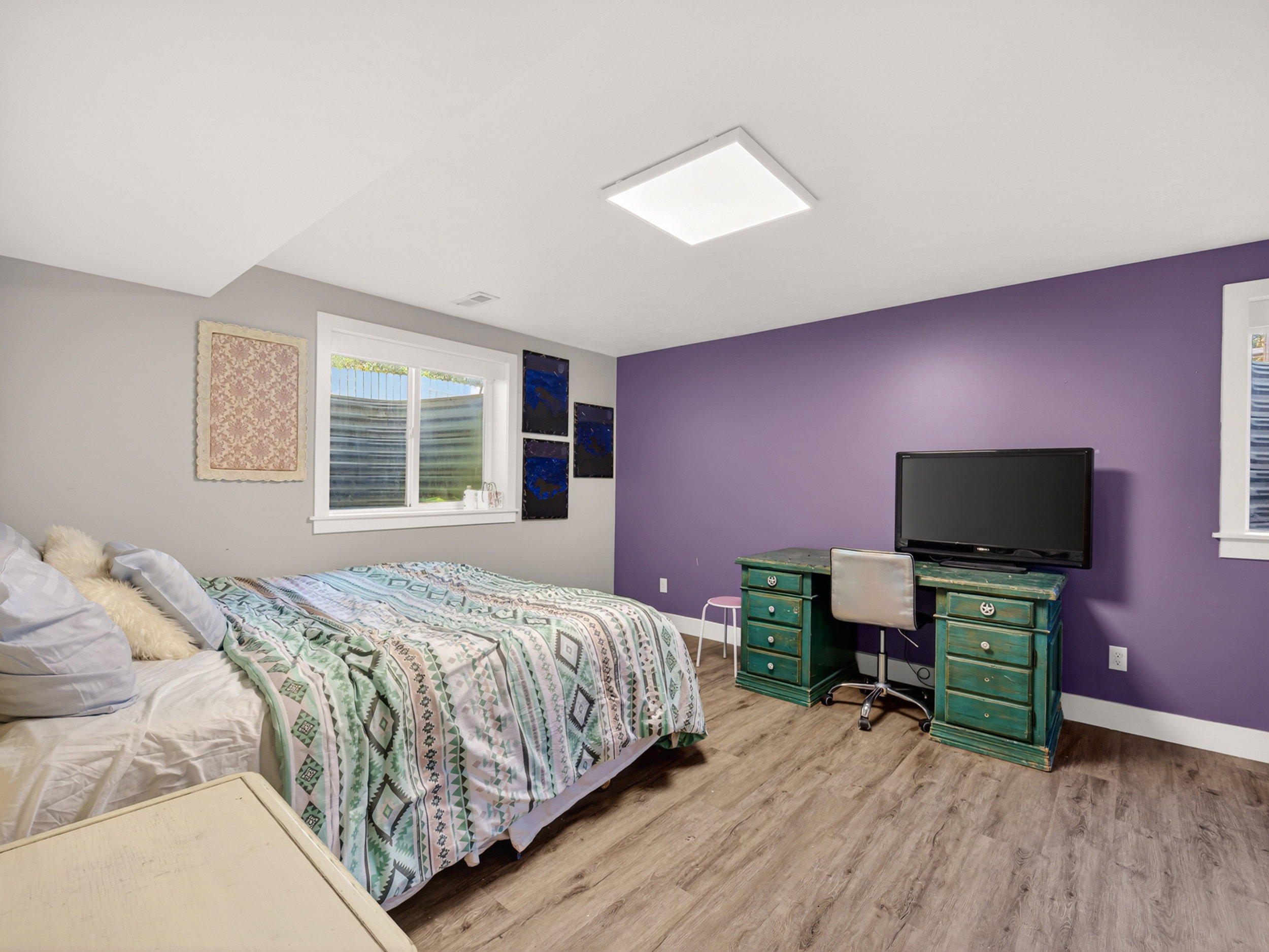 Spacious room featuring wood-finish flooring, a contemporary flush-mount ceiling light, and a window with a window well