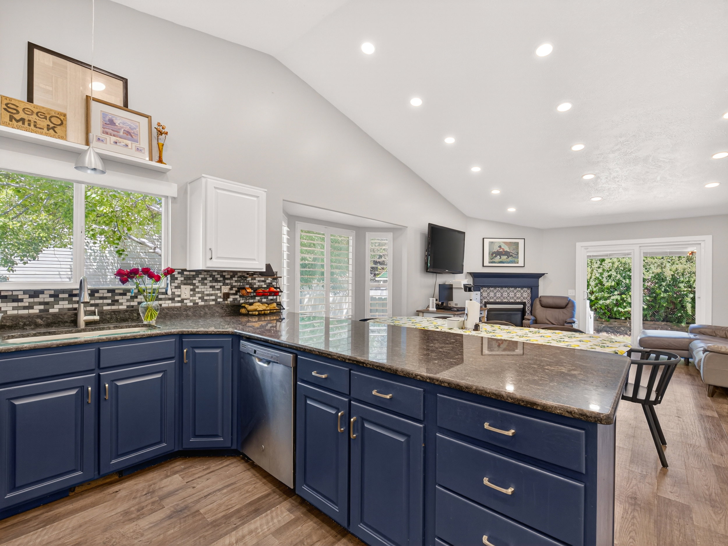 Kitchen featuring wood-finish flooring, dark stone countertops, a mosaic tile backsplash, blue lower cabinetry, and white upper cabinetry
