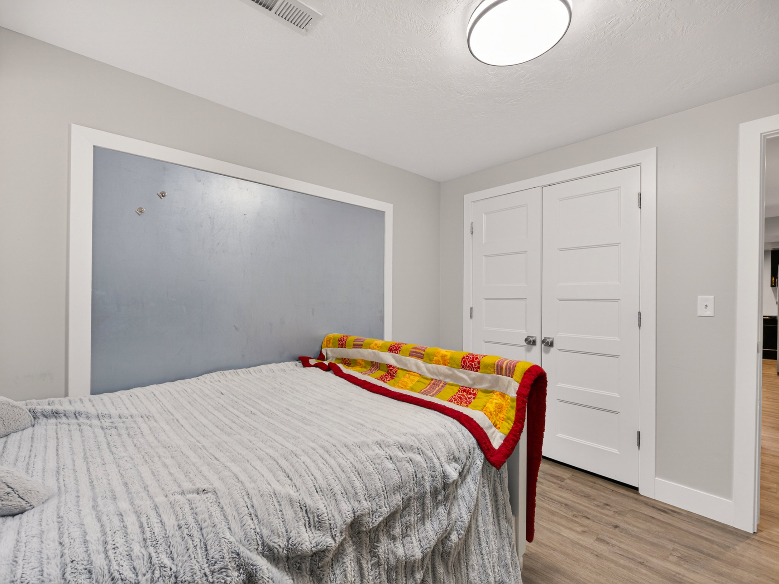 Recessed wall feature with light blue paneling, white trim, and wood-finish flooring
