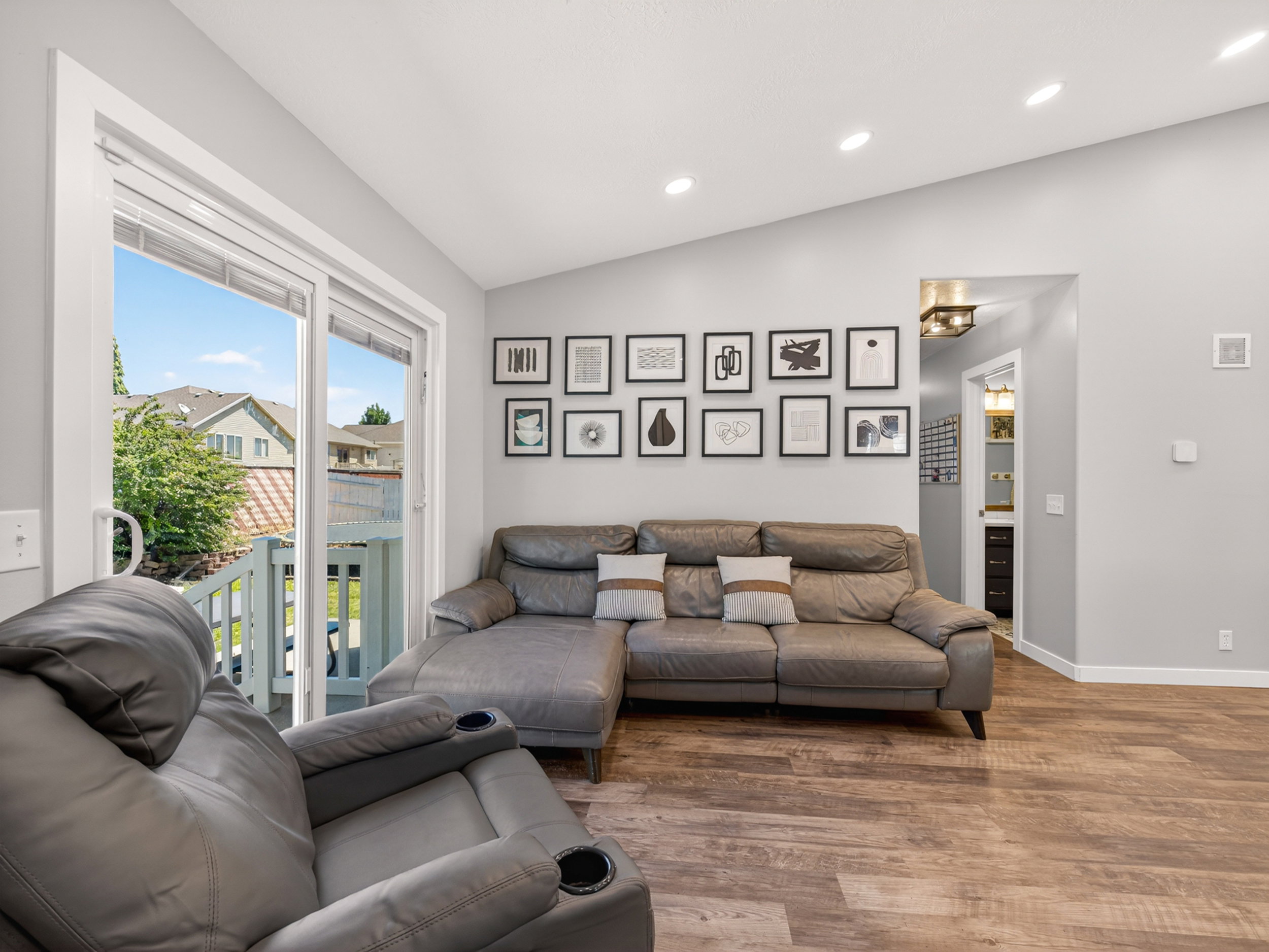 Living area featuring wood-finish flooring, a vaulted ceiling, recessed lighting, and a glass sliding door leading to an outdoor space