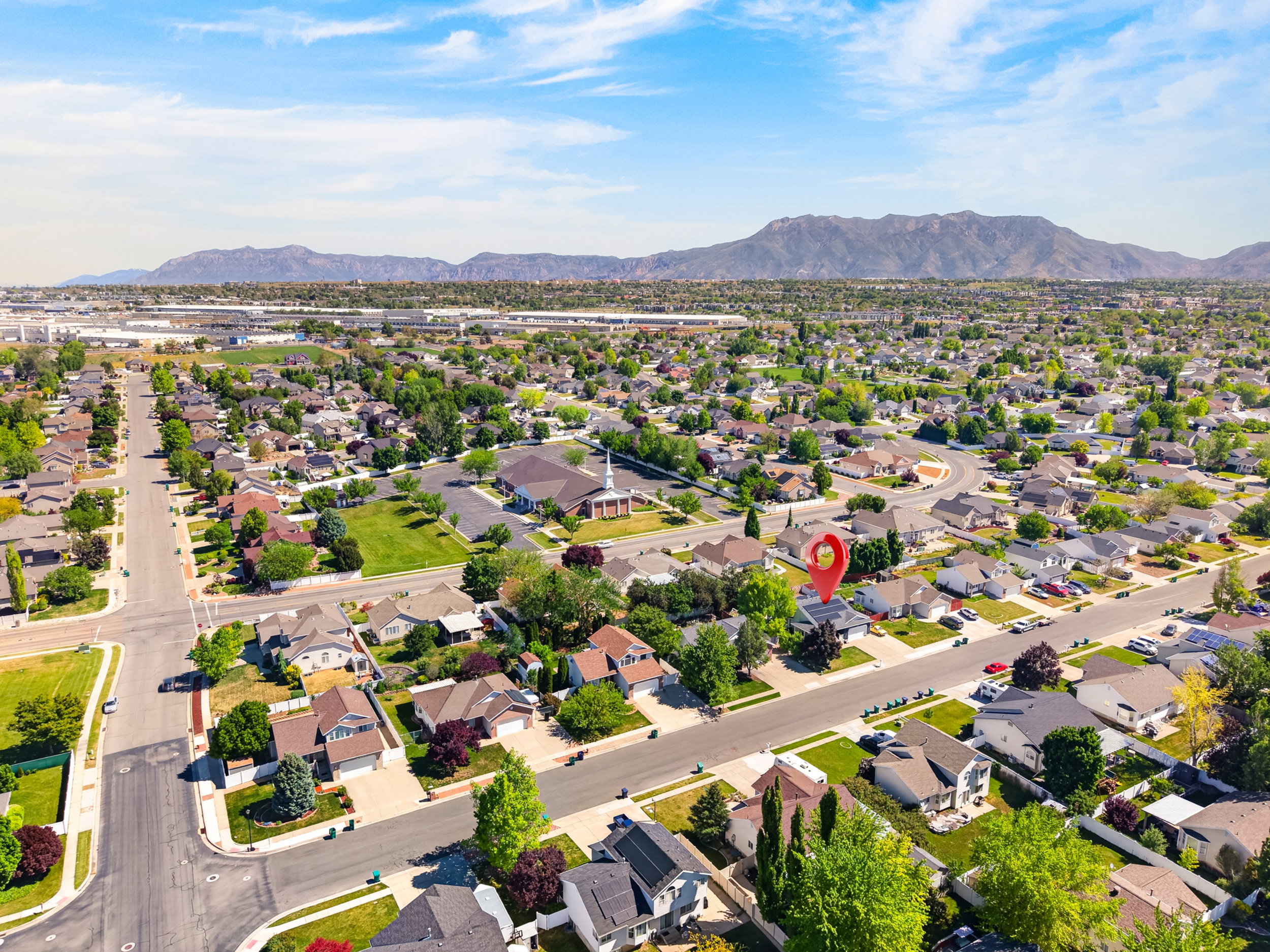 Residential neighborhood with mature trees and paved streets, featuring a distant mountain range