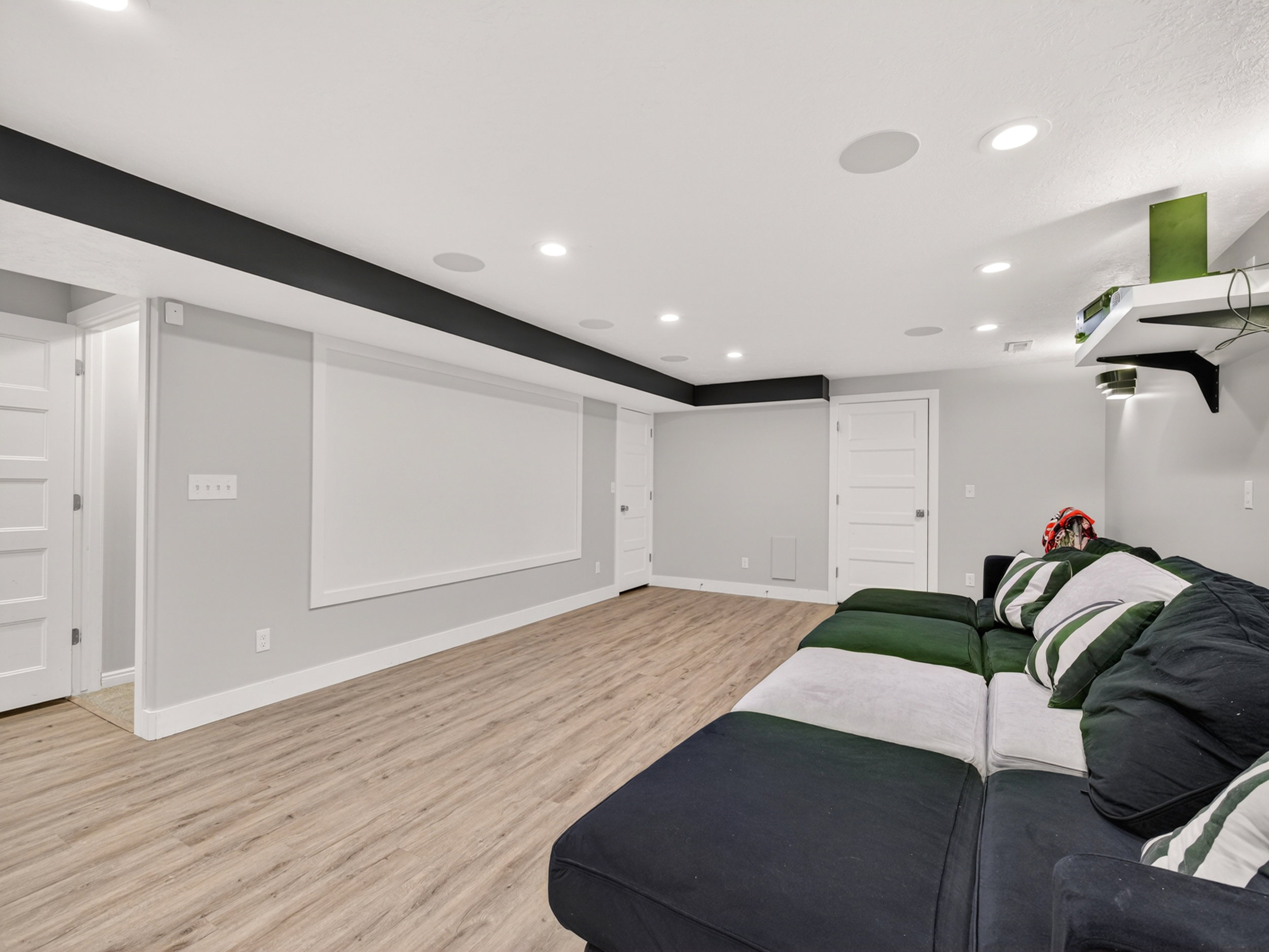 Spacious room featuring wood-finish flooring, recessed lighting, built-in ceiling speakers, and white trim molding