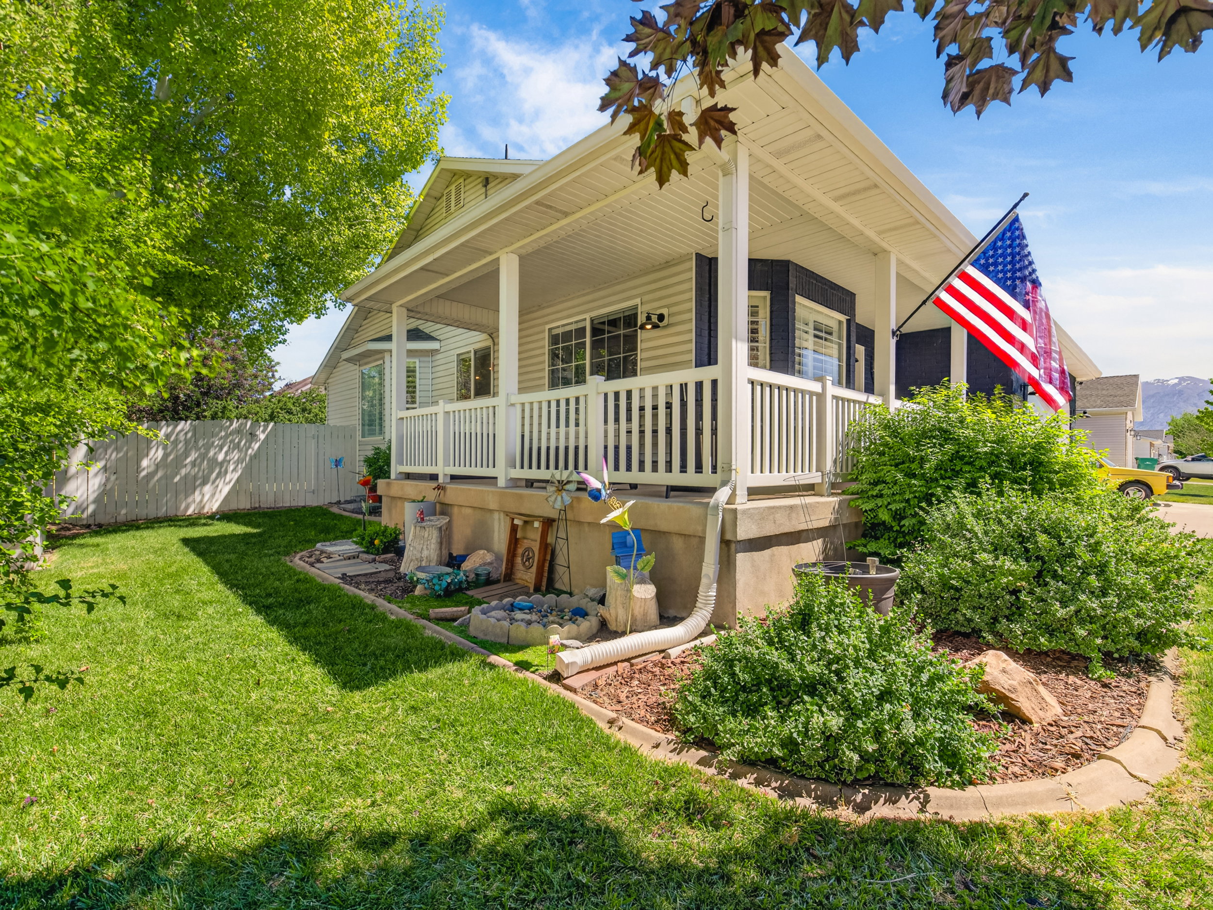 Front porch with white railings and columns, featuring a bay window with dark shutters