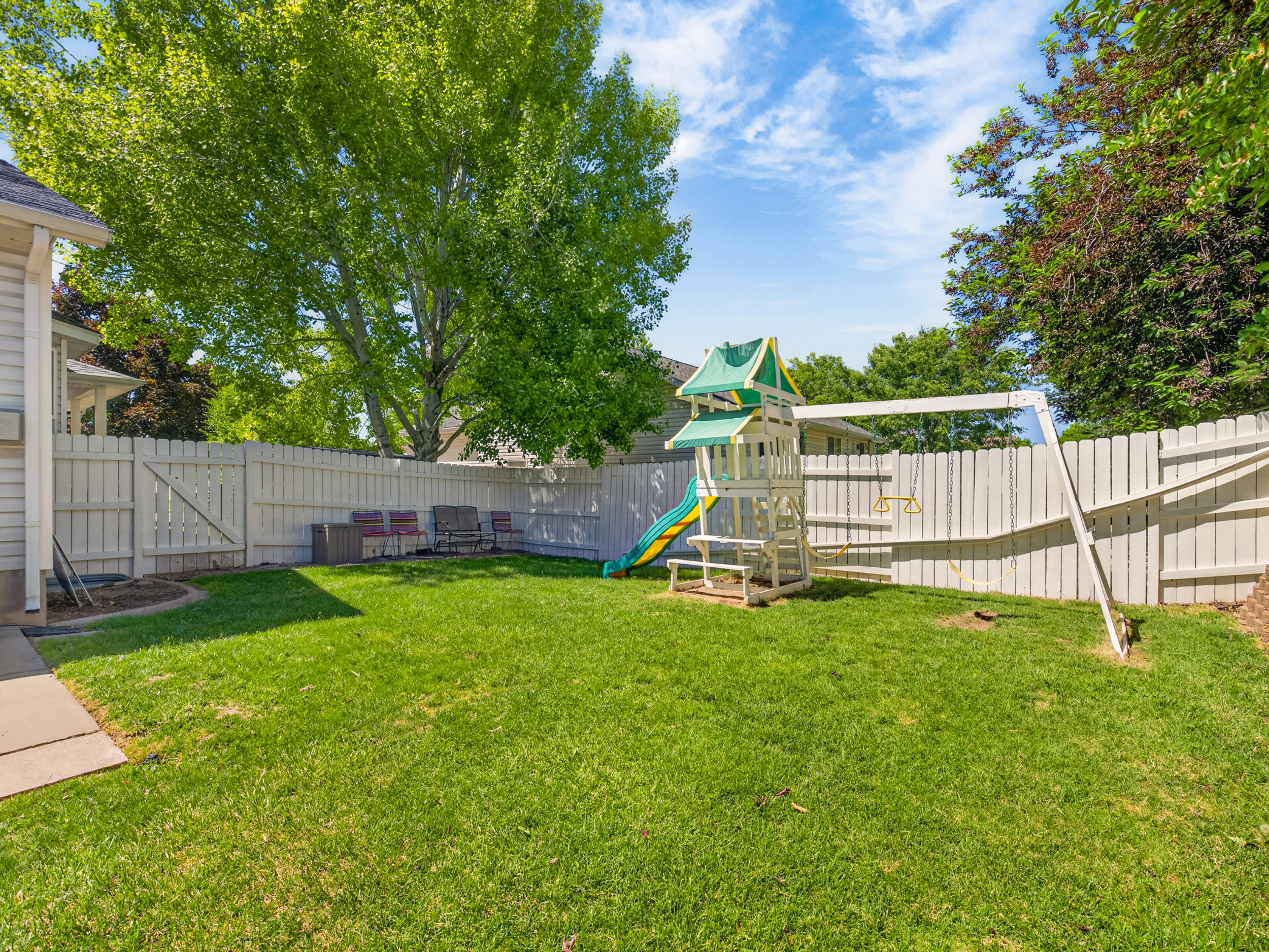 Expansive grassy backyard featuring a full perimeter privacy fence and mature trees