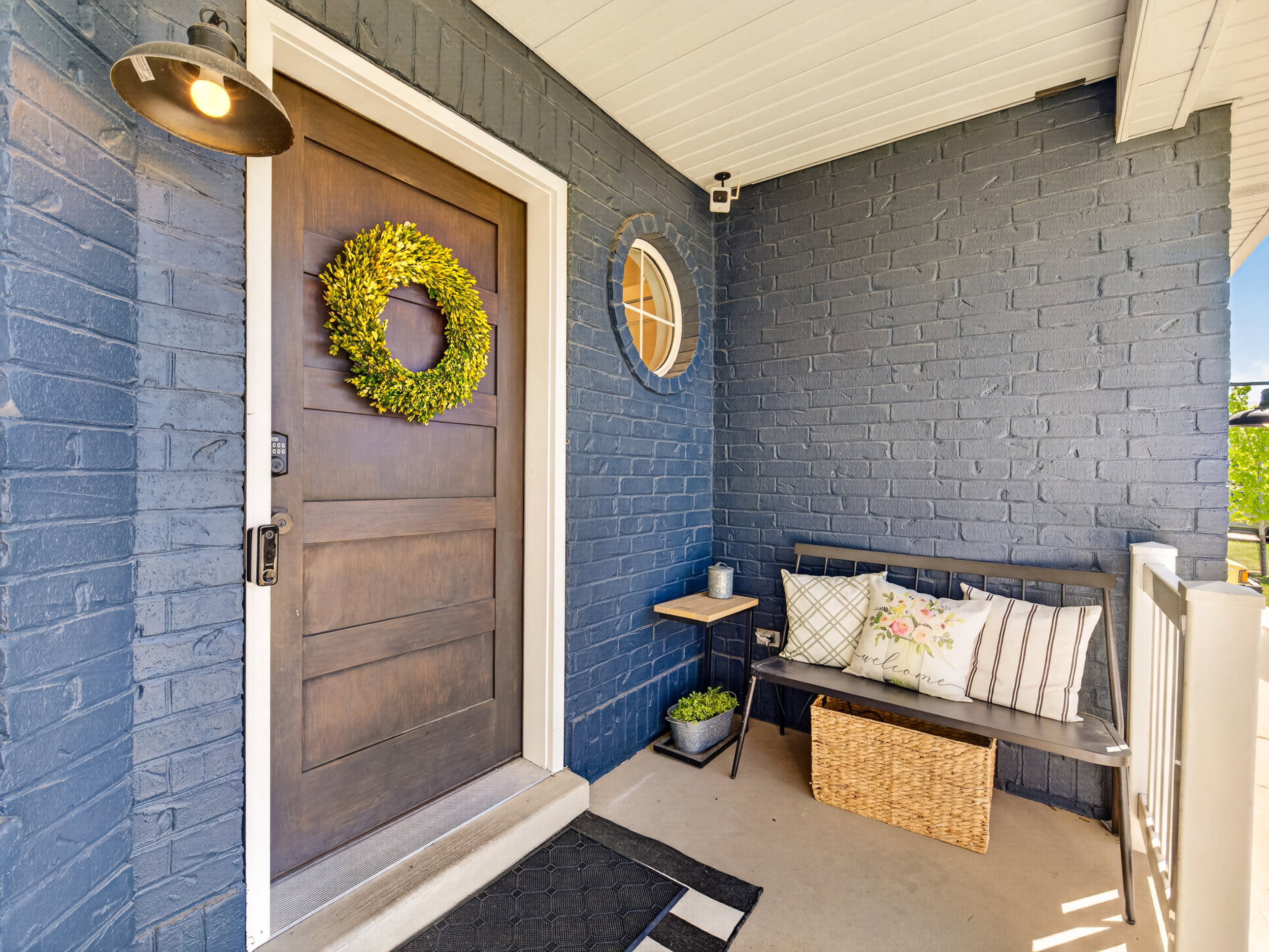 Covered front entry featuring dark-toned painted brick, a solid wood-panel door, and a round accent window