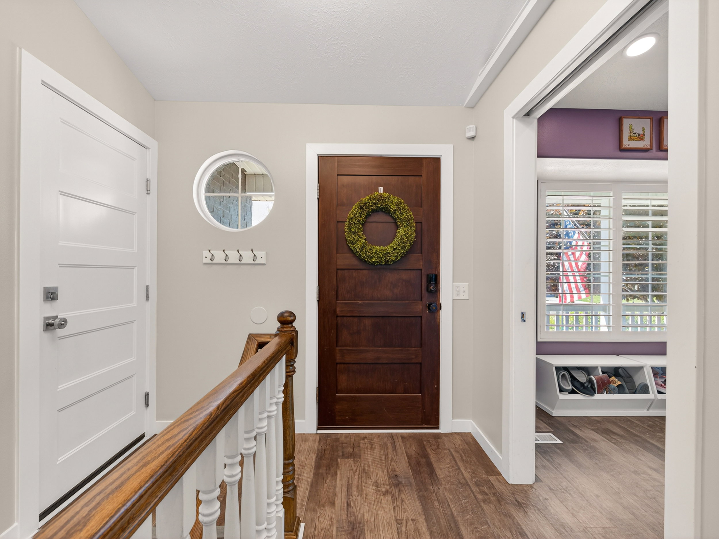 Inviting entryway featuring wood-finish flooring, a solid wood entry door, and a circular accent window