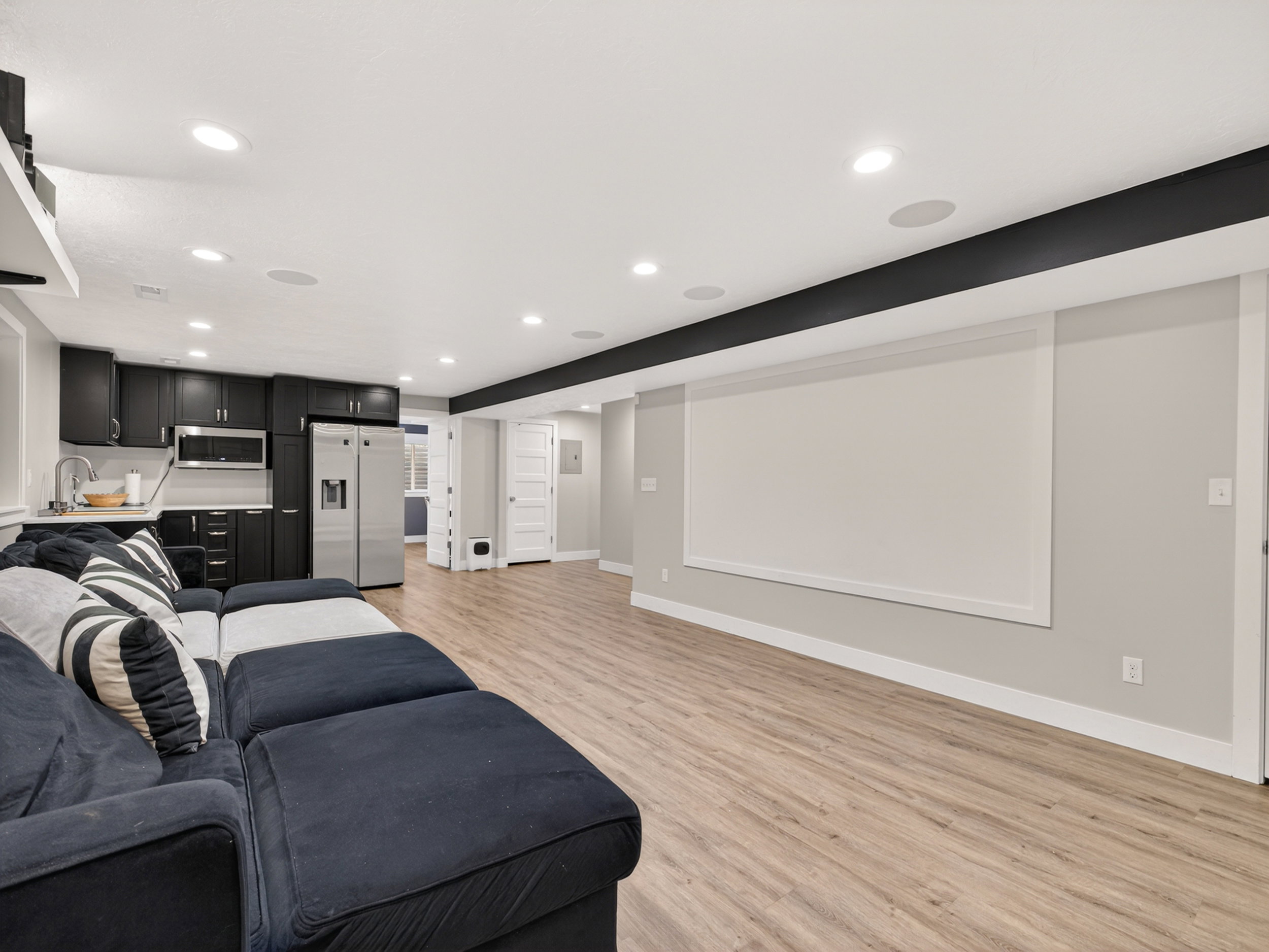 Spacious entertainment room featuring wood-finish flooring, recessed lighting, and an integrated projection screen