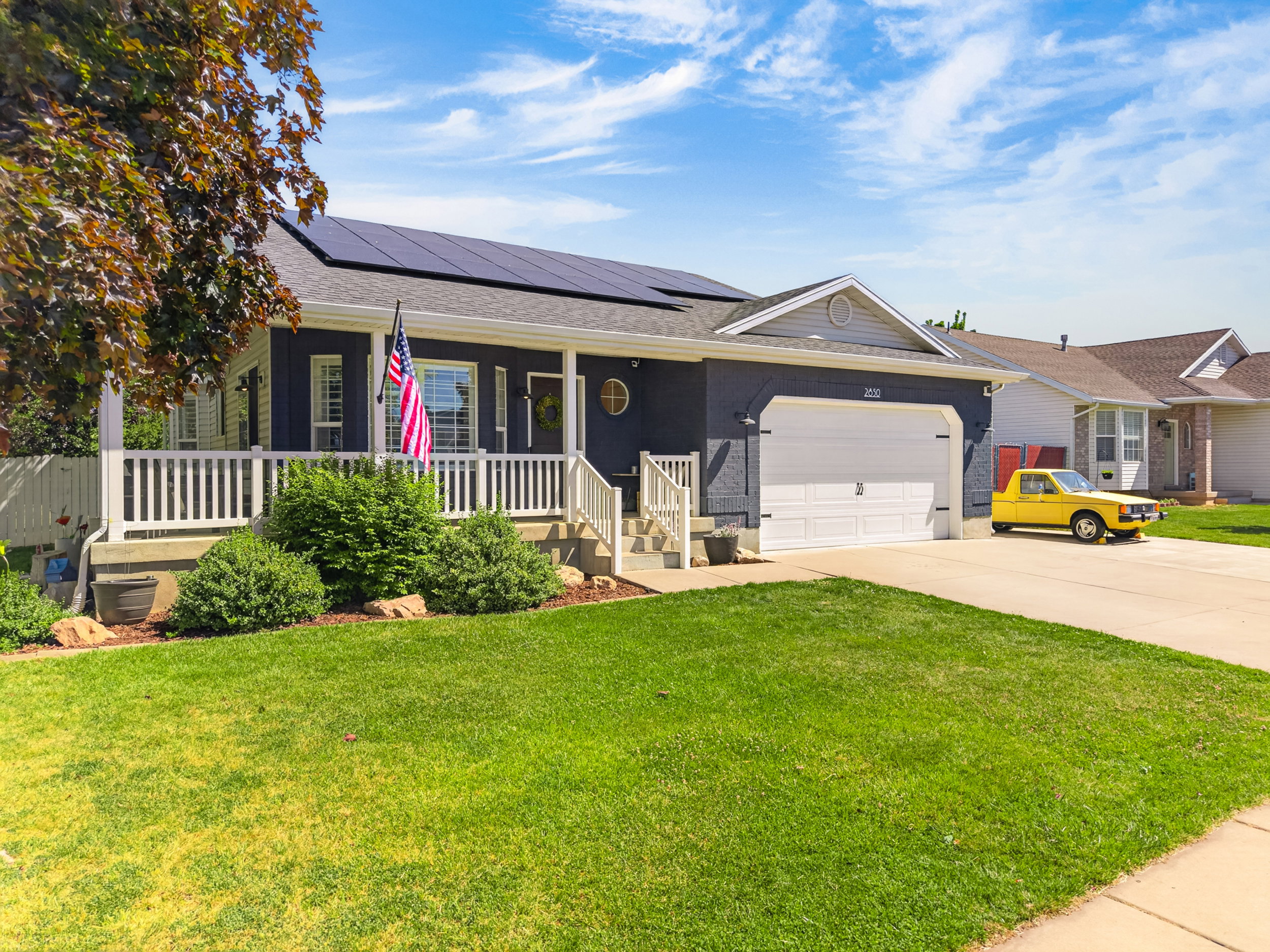 Single-story residence featuring a dark-toned exterior, white porch railing, and a covered front porch