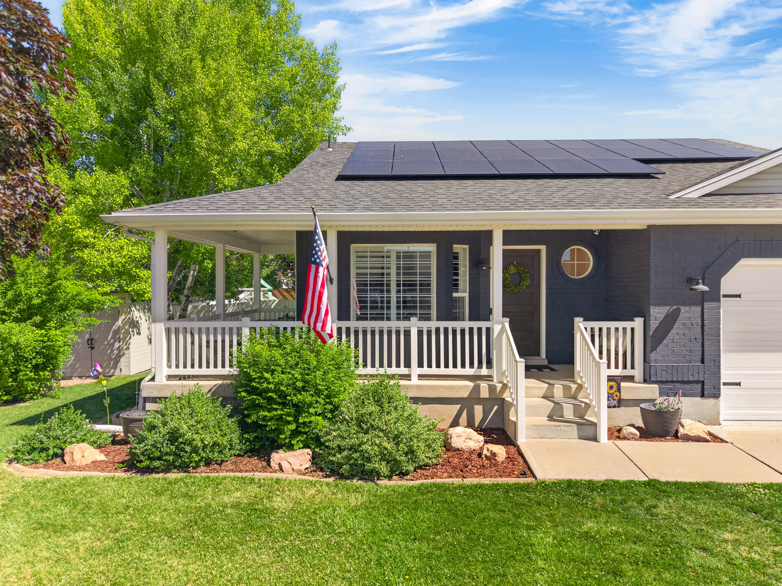 Single-story residence featuring a covered front porch with white railing, a dark entry door, and a circular window accent