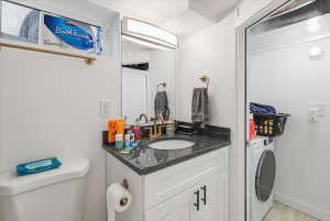 Vanity with a dark stone-look countertop, integrated sink, and gold-tone faucet