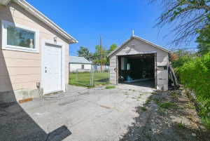 Two detached structures featuring light-colored siding and a concrete driveway