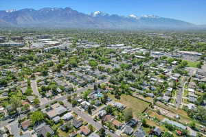 Expansive aerial perspective showcasing a residential neighborhood with tree-lined streets, surrounded by commercial and multi-unit properties