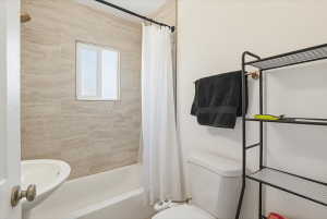 Bathroom featuring a white bathtub, pedestal sink, and toilet