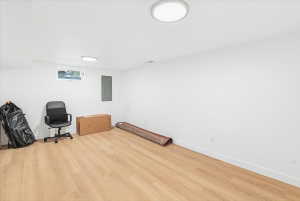 Spacious room with light wood-finish flooring, white walls, and recessed lighting