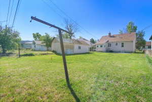 Expansive rear yard featuring a large grass area, a detached auxiliary building, and a paved patio area