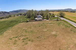 Expansive open land featuring a split-rail fence, mature trees, and mountainous terrain in the distance