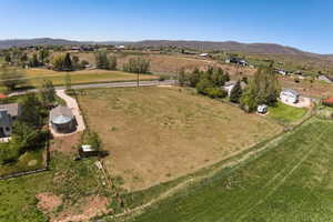 Expansive land parcel featuring open fields, distant mountain terrain, and established road access