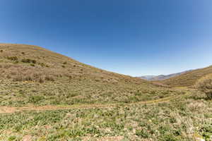 Expansive natural terrain featuring rolling hills and distant mountain ranges under a clear sky
