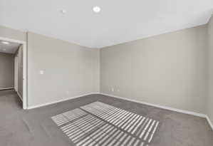 Spacious room featuring gray wall-to-wall carpeting and neutral-toned painted walls