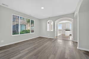 Spacious room featuring wood-finish flooring, light gray wall tones, and recessed lighting