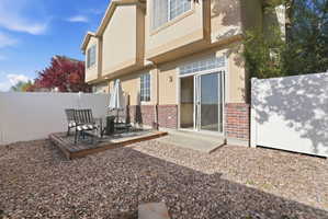 Private outdoor patio featuring a wooden deck, sliding glass door access, and a rock-covered yard