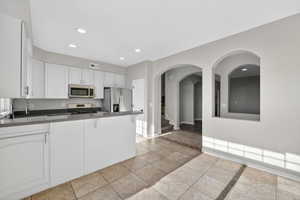 Open-concept kitchen with recessed lighting, white cabinetry, dark countertops, and stainless steel appliances