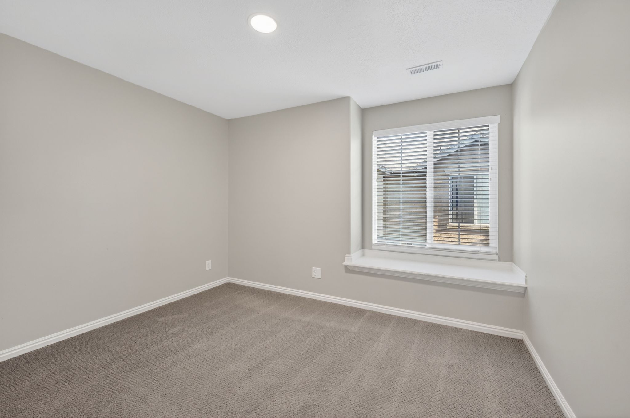 Carpeted room featuring a window with horizontal blinds and a window seat