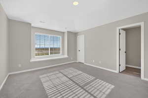 Spacious room featuring neutral paint, gray carpeting, a large window with blinds, and recessed lighting