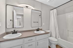 Bathroom featuring a dual vanity with white cabinetry and dark countertops