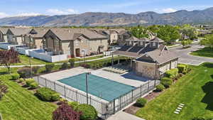 Community swimming pool with safety cover, surrounding iron fencing, and a nearby clubhouse featuring a covered patio