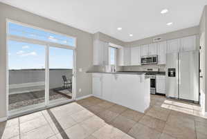 Kitchen featuring white cabinetry, stainless steel appliances, and an island with a dark countertop