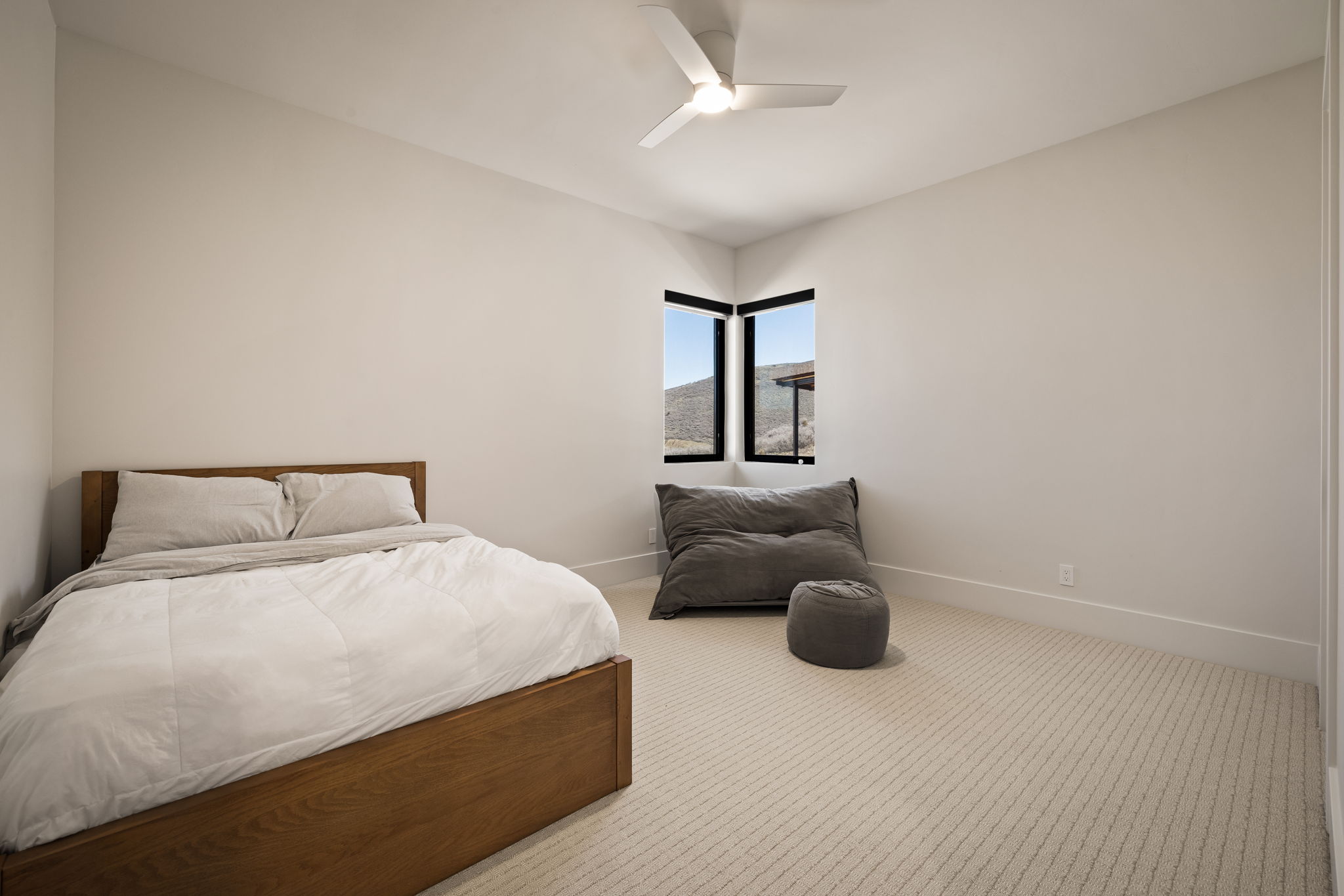 Corner window placement showcasing distant terrain, complemented by soft neutral wall tones and patterned carpeting