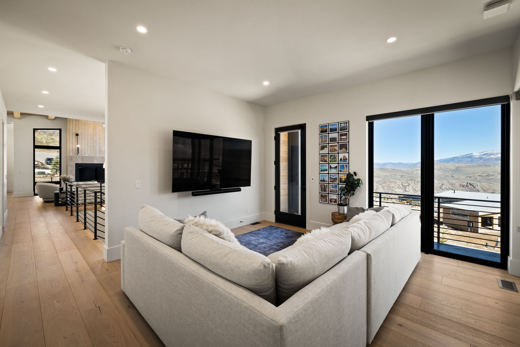 Living area featuring wide-plank wood-finish flooring, recessed lighting, and a large sliding glass door opening to a private balcony