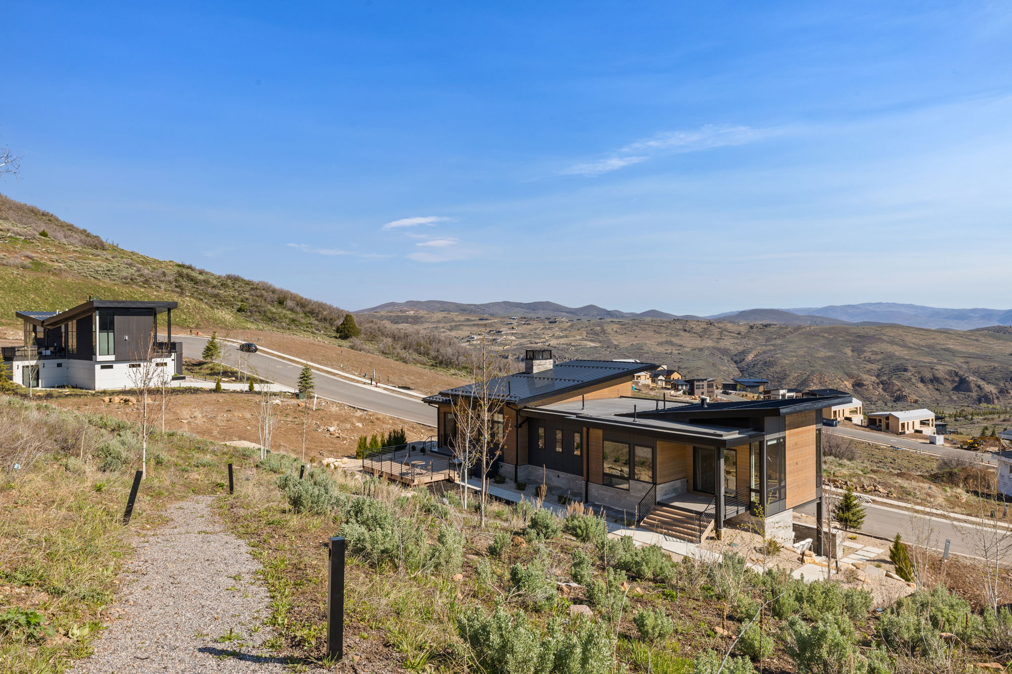 Modern architectural design featuring expansive glass panels, a flat roofline, wood-finish siding, and a stone-clad foundation