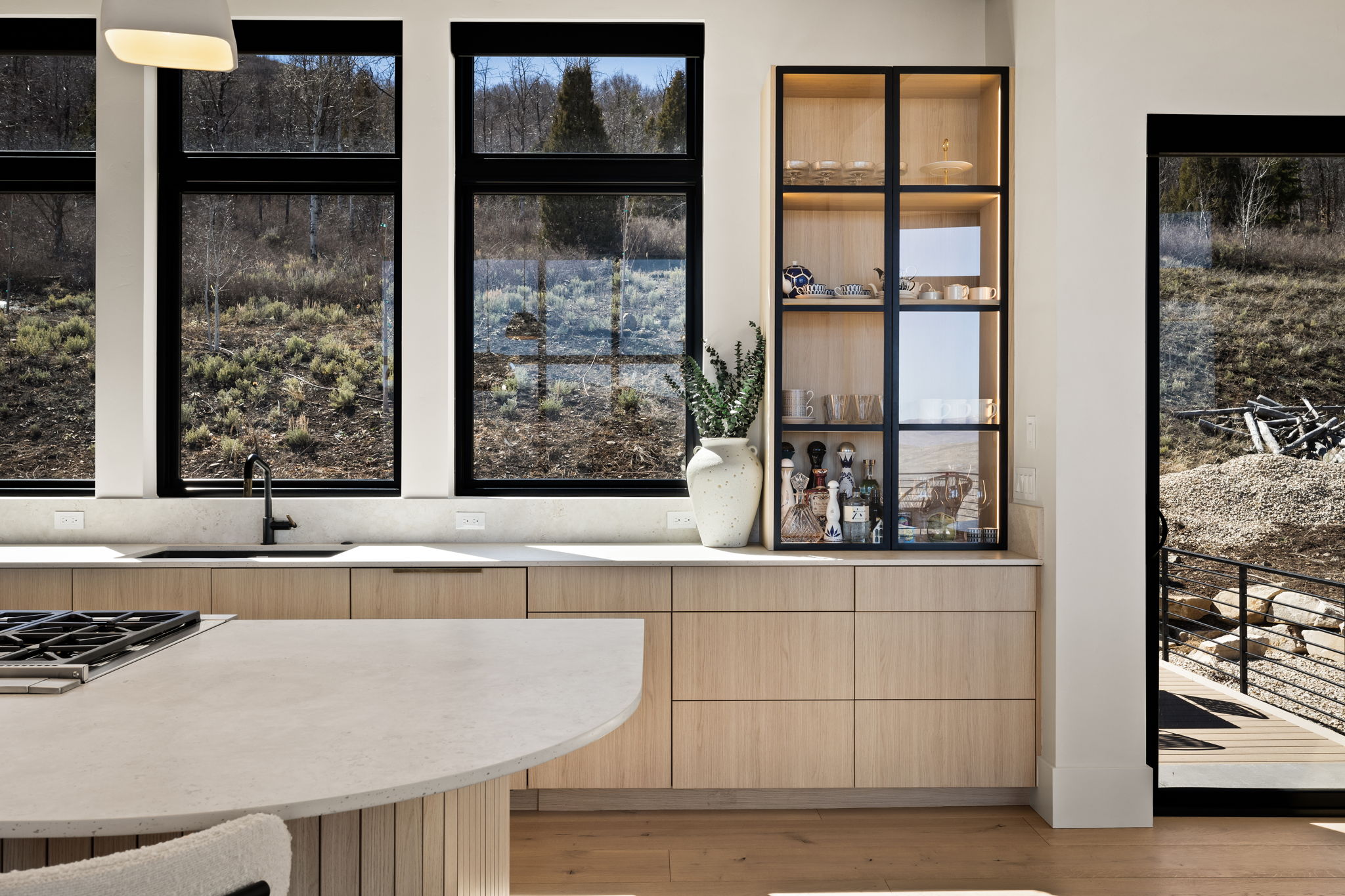 Contemporary kitchen featuring light wood-finish cabinetry, a large kitchen island with a gas cooktop, and light-colored countertops