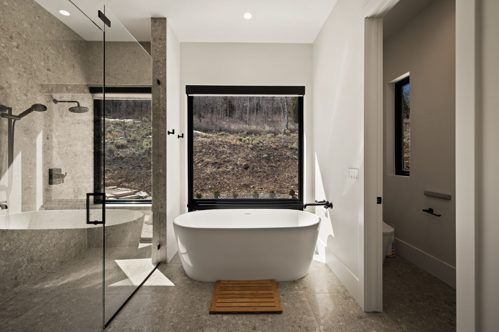 Contemporary bathroom featuring a freestanding soaking tub, a separate shower with a glass enclosure, and a built-in stone tub