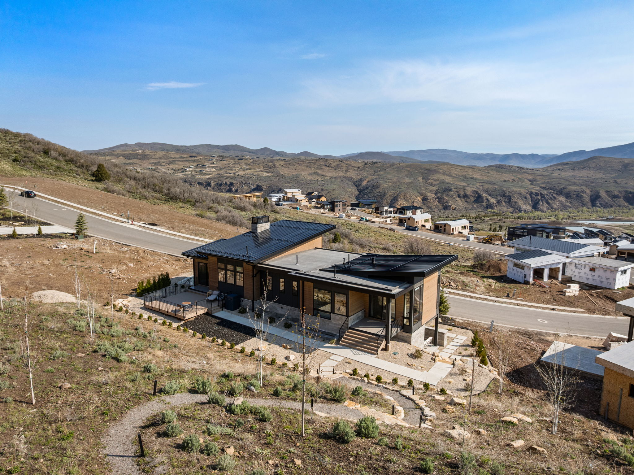 Modern architectural residence featuring a dark-colored roofline, extensive window placement, and a multi-level deck