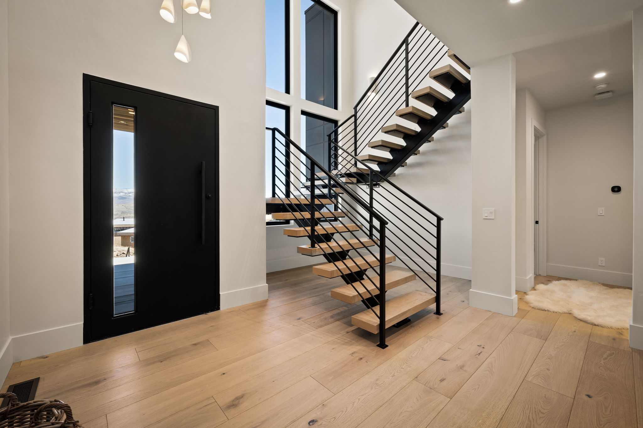 Entryway featuring an open-riser staircase with wood treads and black metal railings