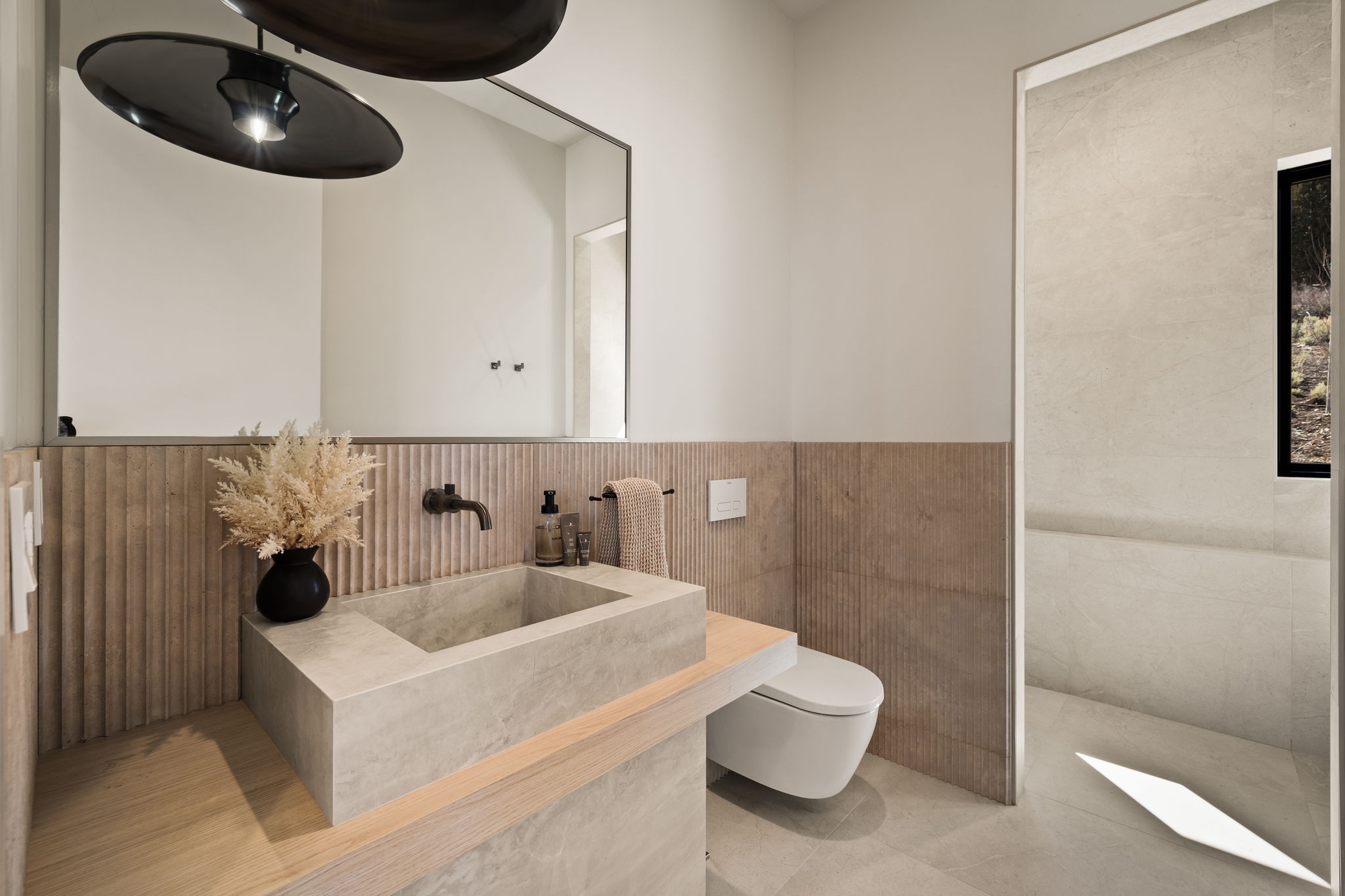 Contemporary bathroom featuring a floating concrete basin, wall-mounted faucet, and slatted wood-finish paneling