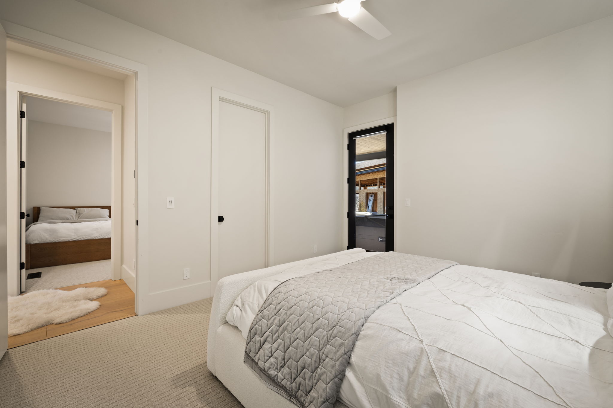 Light-filled room featuring carpeted flooring, a ceiling fan, and a black-framed glass door providing exterior access