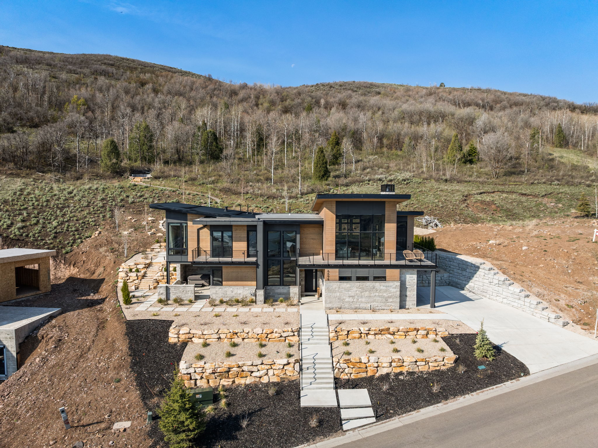 Contemporary hillside residence featuring stacked stone and wood-finish siding