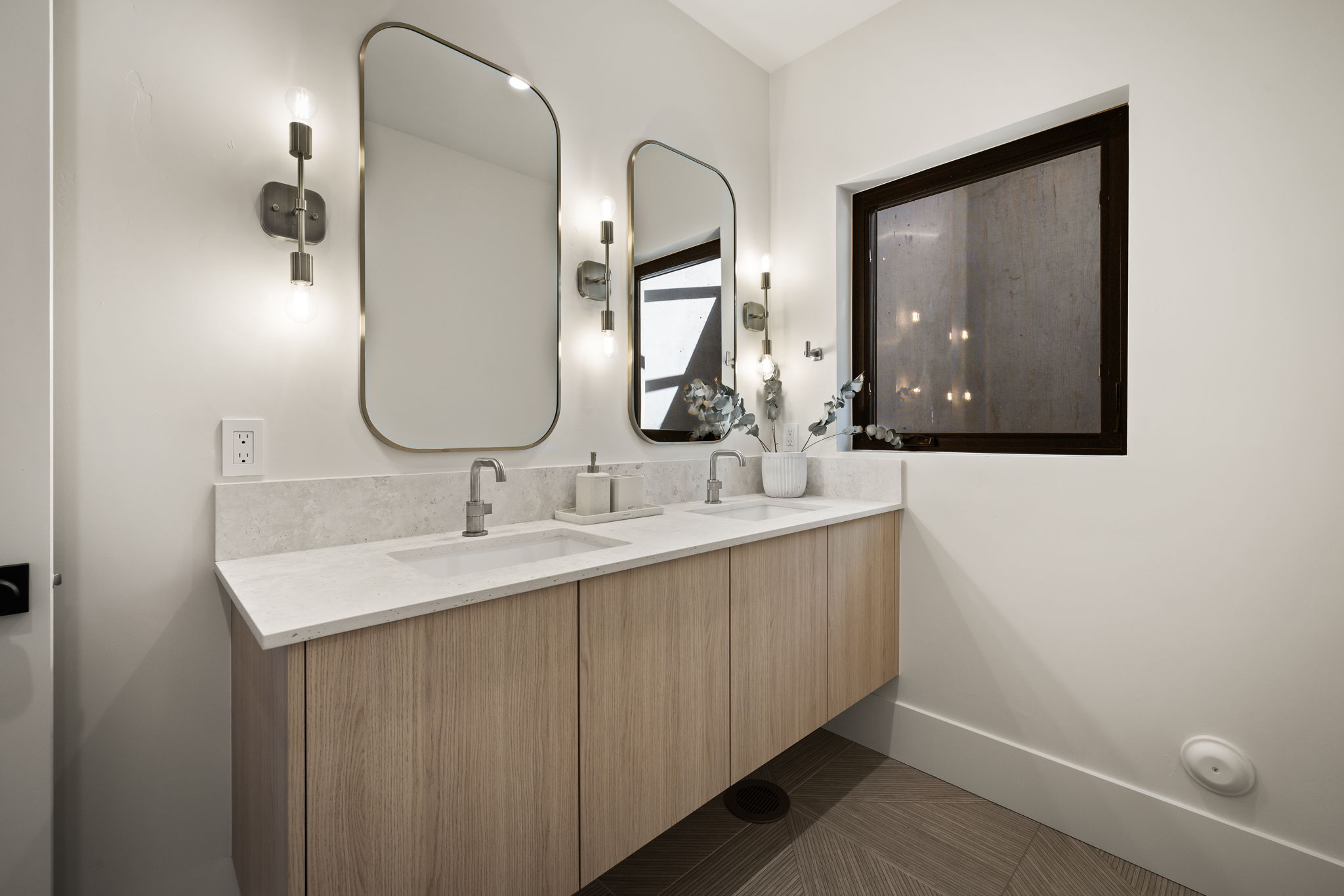 Double vanity with a light wood-finish floating cabinet and stone countertop