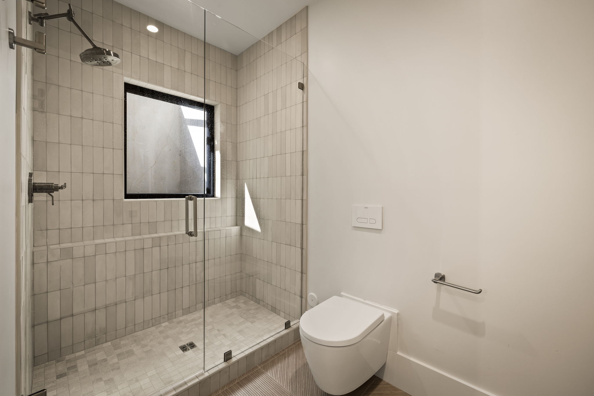 Contemporary shower enclosure featuring full-height vertical tile, a fixed window, and a built-in shower bench