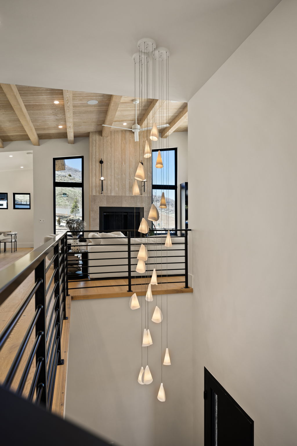 Multi-level drop chandelier illuminating a modern interior with wood-finish flooring